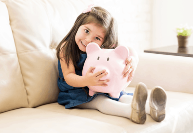 little girl smiling holding piggy bank